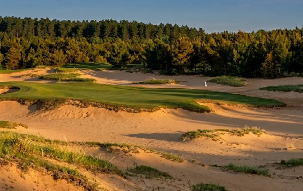 Sand Valley fairway winding through exposed prehistoric sand dunes and native scrub under a wide Wisconsin sky